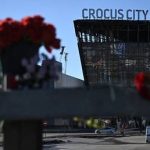Flowers and toys are placed on the roadside in front of the burned-out Crocus City Hall in Moscow Region following a terrorist attack, March 27, 2024.